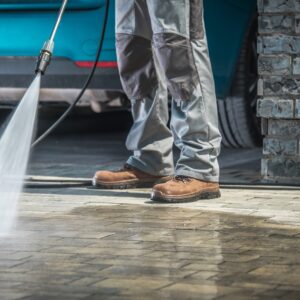 Cobble Stone Driveway Cleaning Using Pressure Washer with Concrete Cleaning Detergent. Closeup Photo.